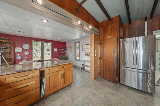 kitchen featuring freestanding refrigerator, recessed lighting, light stone countertops, and brown cabinetry