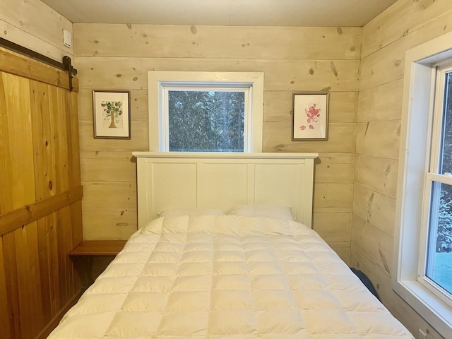 bedroom with wooden walls and a barn door