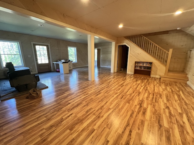 unfurnished living room with wood finished floors, stairs, and wood walls
