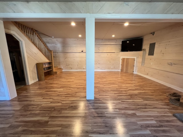 finished below grade area with wood finished floors, wood walls, stairway, recessed lighting, and baseboards
