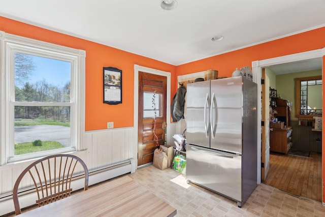 193 Spec Pond Rd, Porter, ME 04068 - kitchen with freestanding refrigerator, a baseboard heating unit, a healthy amount of sunlight, and a wainscoted wall