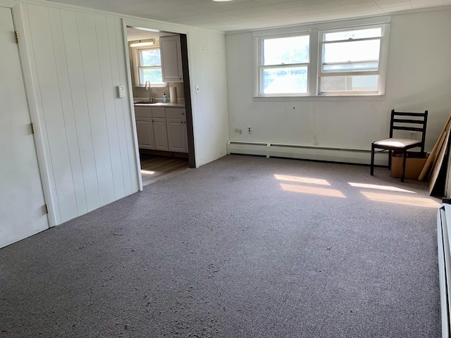 empty room featuring carpet floors, a sink, and a baseboard radiator