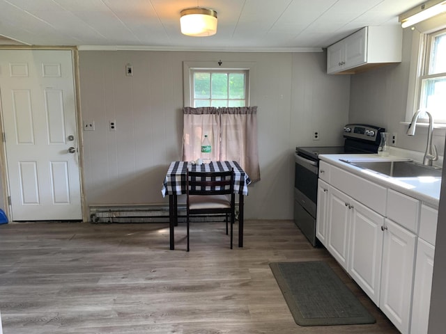 kitchen featuring crown molding, light wood-type flooring, stainless steel electric range, white cabinets, and a sink
