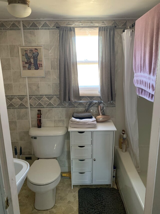 bathroom with tile walls, shower / bath combo, and toilet