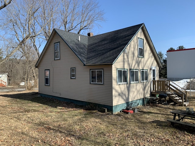 rear view of house featuring roof with shingles, a yard, and a chimney