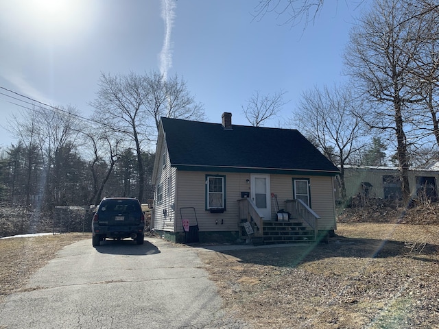 view of front facade featuring driveway and a chimney
