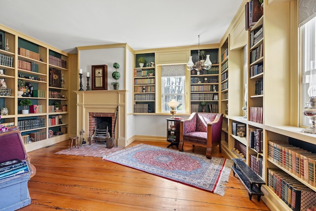 875 N Parish Rd, Turner, ME 04282 - sitting room with a brick fireplace, hardwood / wood-style flooring, built in shelves, and a notable chandelier