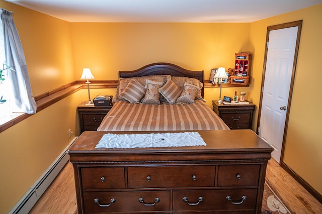 bedroom featuring baseboard heating, light wood-style flooring, and baseboards