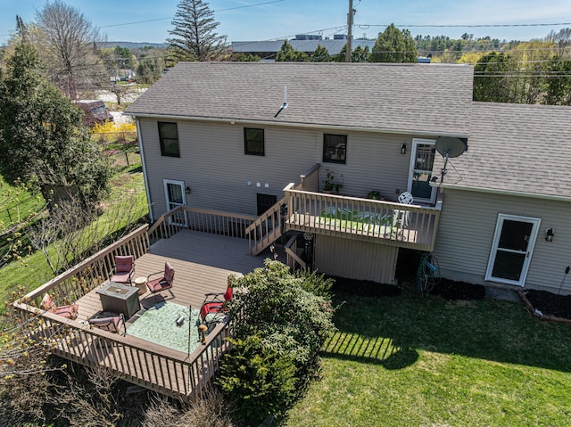 rear view of house with a deck, a lawn, and a shingled roof