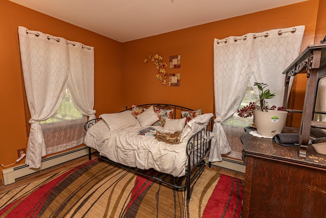 bedroom with baseboard heating and wood finished floors