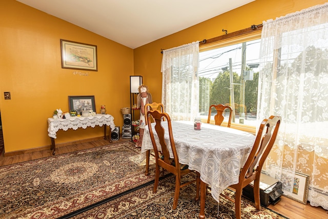 dining space featuring vaulted ceiling and wood finished floors
