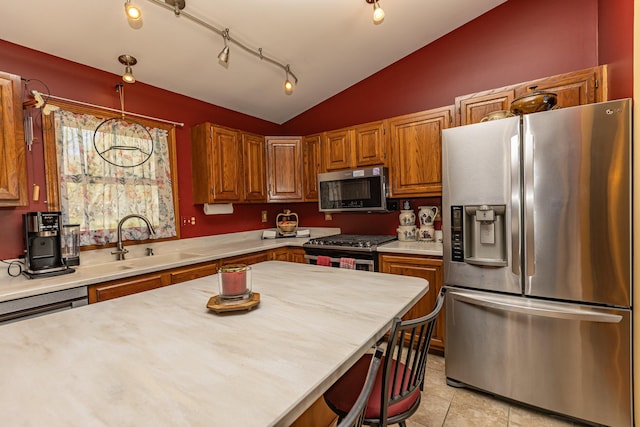 kitchen featuring appliances with stainless steel finishes, a sink, light countertops, vaulted ceiling, and light tile patterned floors