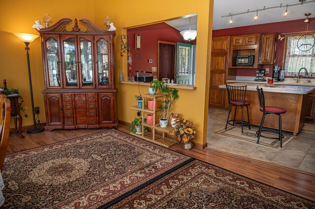 bar with black microwave, light wood-style floors, baseboards, and a sink