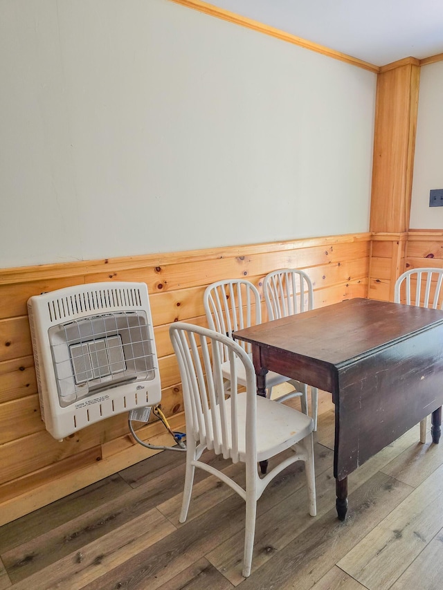dining area featuring ornamental molding, heating unit, and wood finished floors