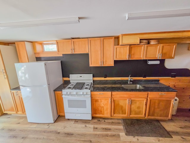 kitchen with light wood-style floors, a sink, and white appliances