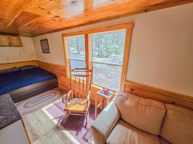 bedroom featuring wooden ceiling, a wainscoted wall, hardwood / wood-style flooring, and wood walls