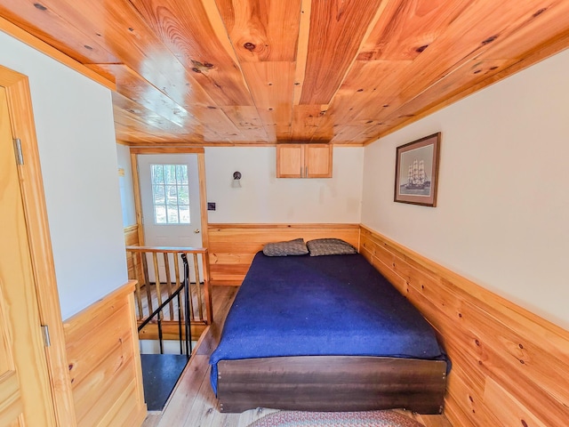 bedroom with wood walls, wood ceiling, and wainscoting