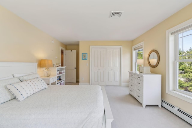 bedroom featuring visible vents, a closet, a baseboard heating unit, and multiple windows