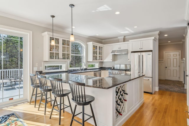 kitchen with light wood-style floors, appliances with stainless steel finishes, glass insert cabinets, under cabinet range hood, and white cabinetry