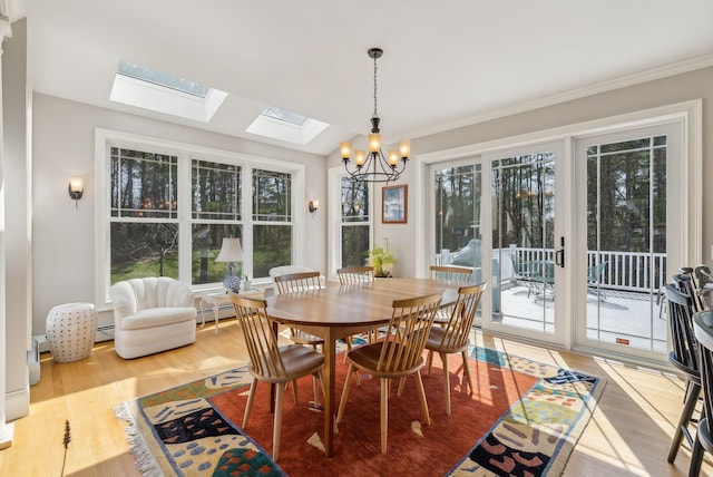 dining room featuring an inviting chandelier, wood finished floors, a baseboard radiator, a skylight, and ornamental molding