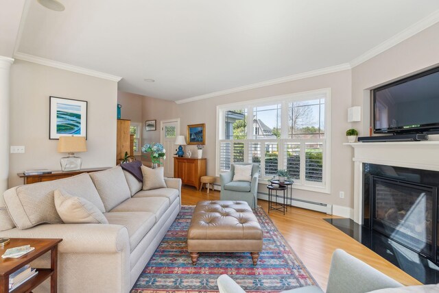 living room featuring a baseboard heating unit, ornamental molding, wood finished floors, and a glass covered fireplace