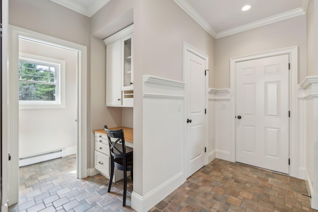 interior space with ornamental molding, baseboard heating, stone finish floor, recessed lighting, and built in desk