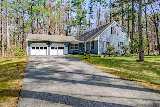 ranch-style home with a garage, a front lawn, driveway, and a chimney