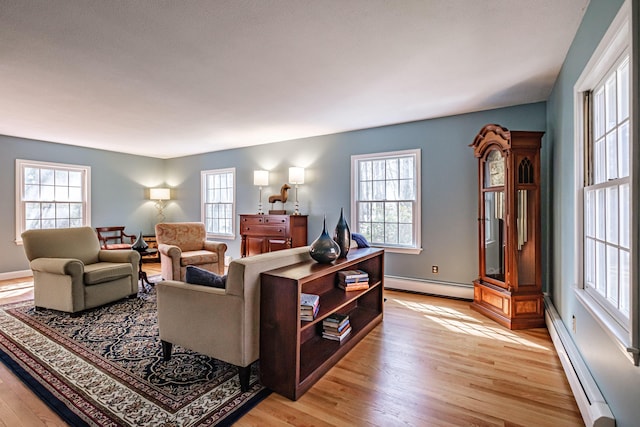 living room featuring plenty of natural light, a baseboard radiator, light wood-style floors, and baseboard heating