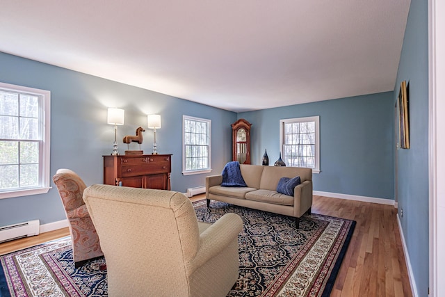 living room with wood finished floors, baseboards, and a baseboard heating unit