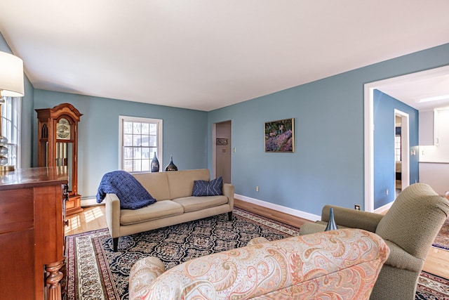 living area with baseboards, a baseboard heating unit, and wood finished floors