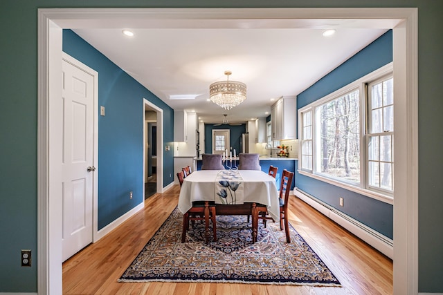 dining space with light wood-type flooring, baseboards, a baseboard radiator, a notable chandelier, and recessed lighting
