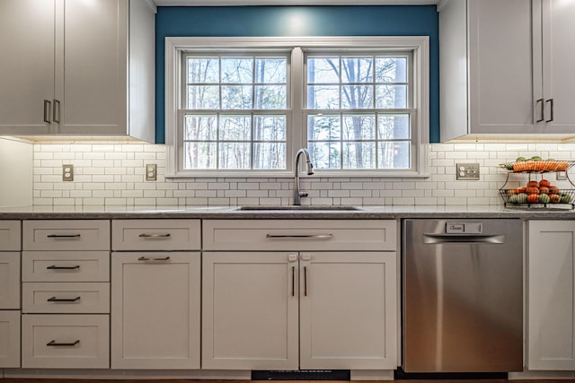 kitchen with a sink, dishwasher, light stone countertops, and tasteful backsplash