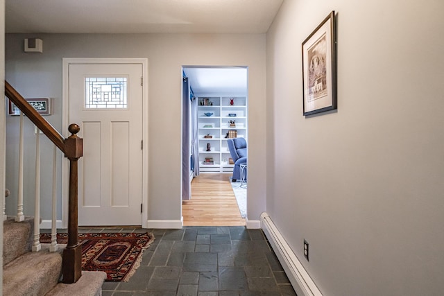 foyer with baseboards, a baseboard radiator, stairs, and stone tile flooring