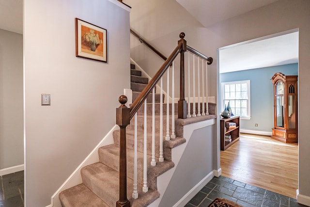 staircase with stone tile flooring, baseboards, and baseboard heating