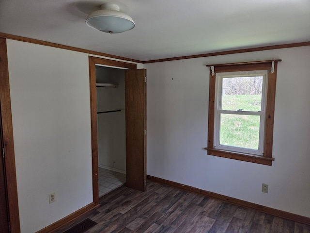 unfurnished bedroom with baseboards, a closet, crown molding, and wood finished floors