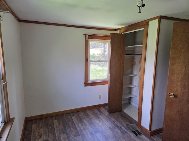 unfurnished bedroom with baseboards, ornamental molding, visible vents, and wood finished floors