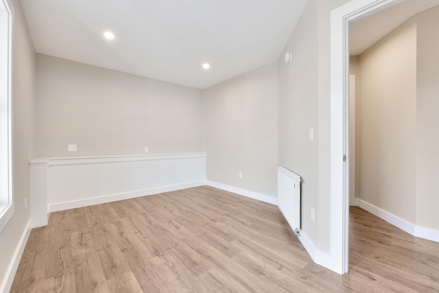 spare room featuring recessed lighting, radiator, baseboards, and light wood-type flooring