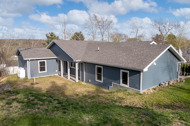 rear view of property with a lawn and roof with shingles
