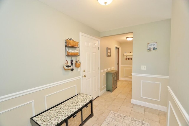 interior space featuring a decorative wall, light tile patterned floors, and a wainscoted wall