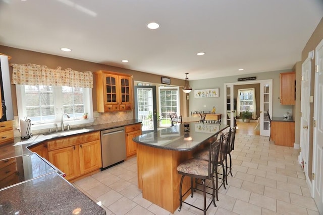 kitchen with stainless steel dishwasher, a breakfast bar, a kitchen island, and a wealth of natural light