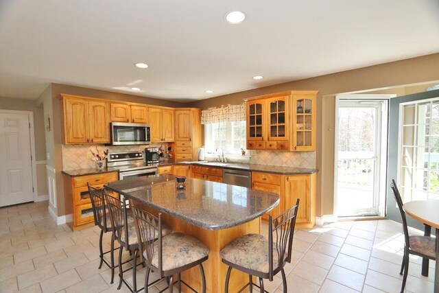 kitchen with a sink, appliances with stainless steel finishes, a breakfast bar, and light tile patterned floors
