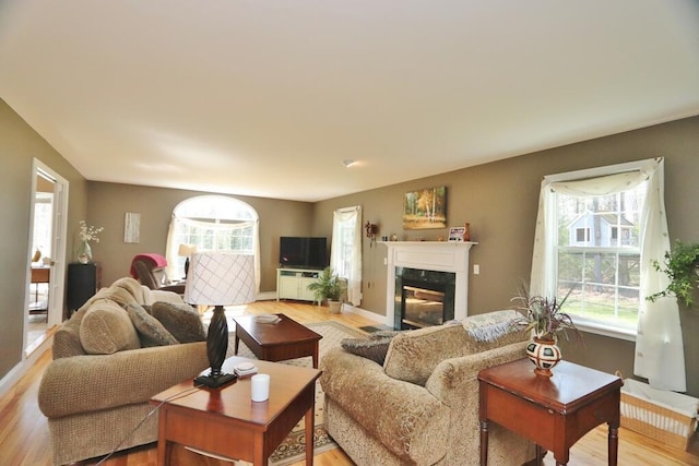living area with a wealth of natural light, light wood finished floors, and a high end fireplace