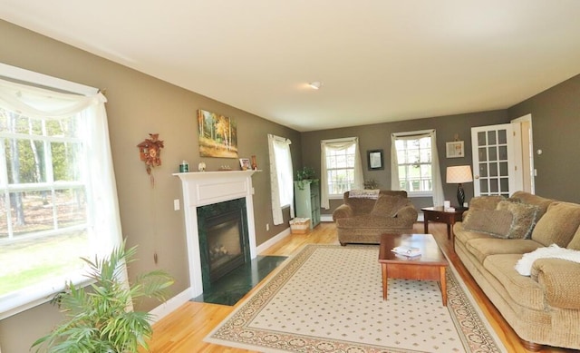 living area with baseboards, light wood-style flooring, and a high end fireplace