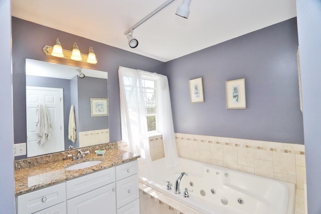 bathroom with track lighting, vanity, and a whirlpool tub