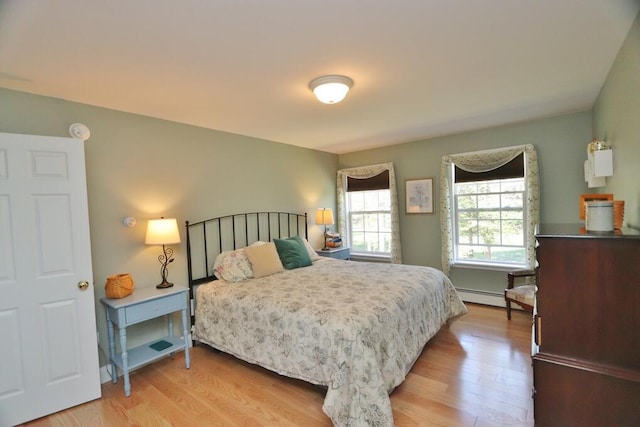 bedroom with light wood-style floors and a baseboard heating unit