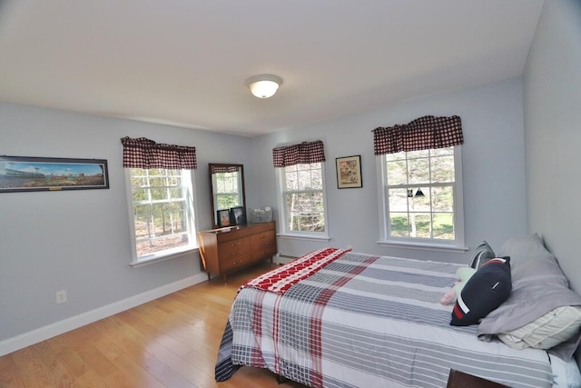 bedroom with baseboards, a baseboard heating unit, and wood finished floors