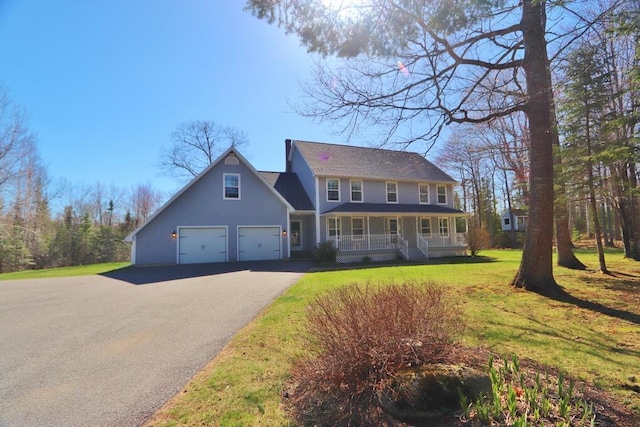 colonial house featuring a garage, covered porch, driveway, and a front yard