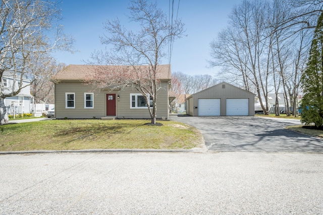 view of front of house featuring a detached garage, an outdoor structure, roof with shingles, and a front lawn