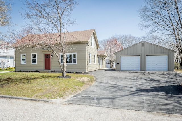 view of front of home with an outbuilding, a front lawn, roof with shingles, and a garage