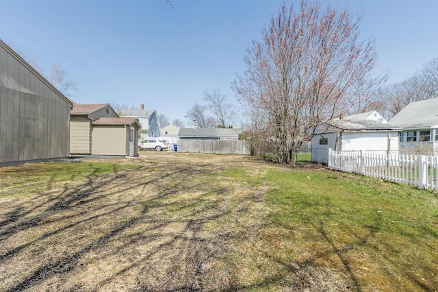 view of yard with fence, an outdoor structure, and a storage unit